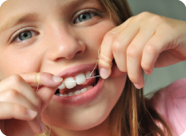 bambina si pulisce i denti con filo interdentale